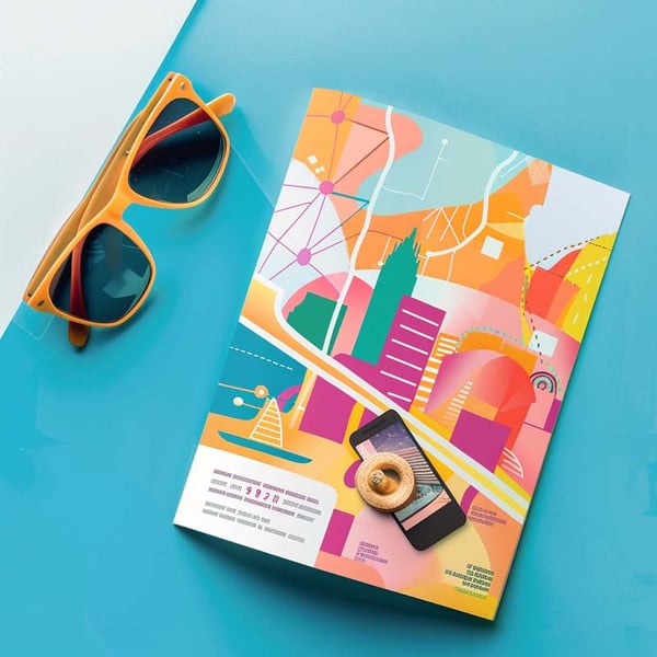 a colorful piece of direct mail sitting on a vivid blue desk, next to a pair of sunglasses